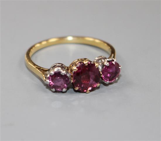 An 18ct and three stone ruby and garnet?? set dress ring, size M, gross 2.7 grams.